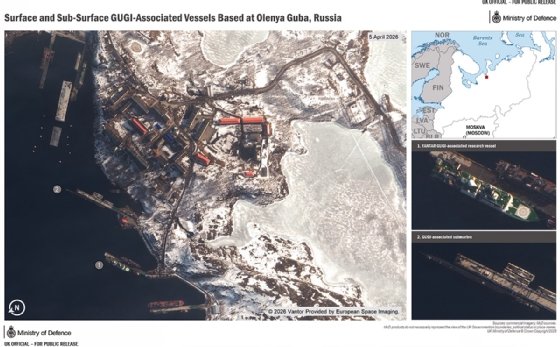 UK MoD image titled ’Surface and sub-surface GUGI-associated vessels based at Olenya Guba, Russia’: main image is overhead shot of Olenya Guba, with the research vessel and submarine show docked. Three images are stacked to the side of main image, one showing a map with Olenya Guba labelled with a red dot, the second is a close-up shot of the research vessel, and the third is a close-up of the submarine. 